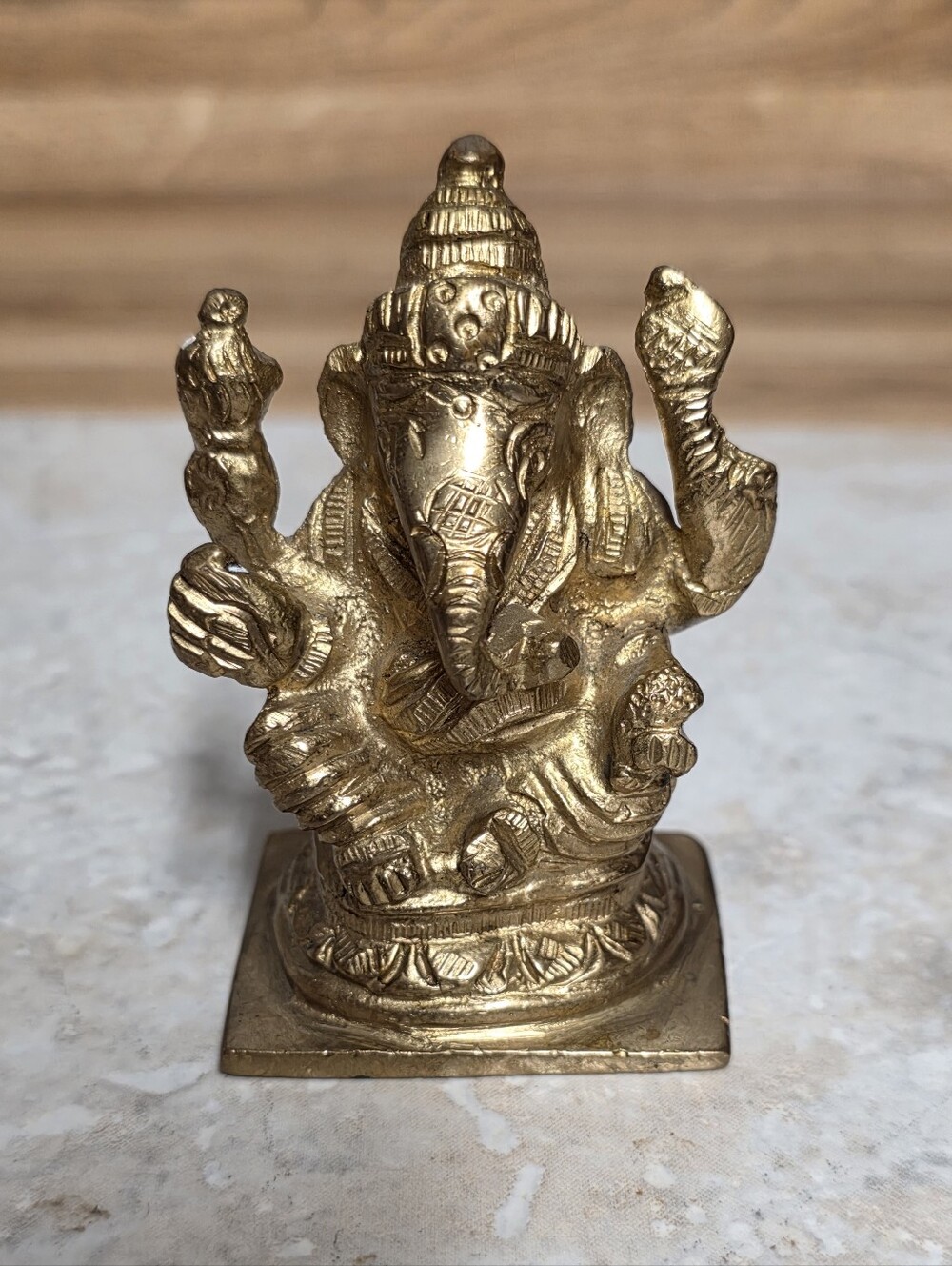 Small handcrafted solid brass statue of Lord Ganesha seated on an ornate square